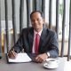 Closeup portrait of smiling middle-aged Indian business man completing form and sitting at cafe table
